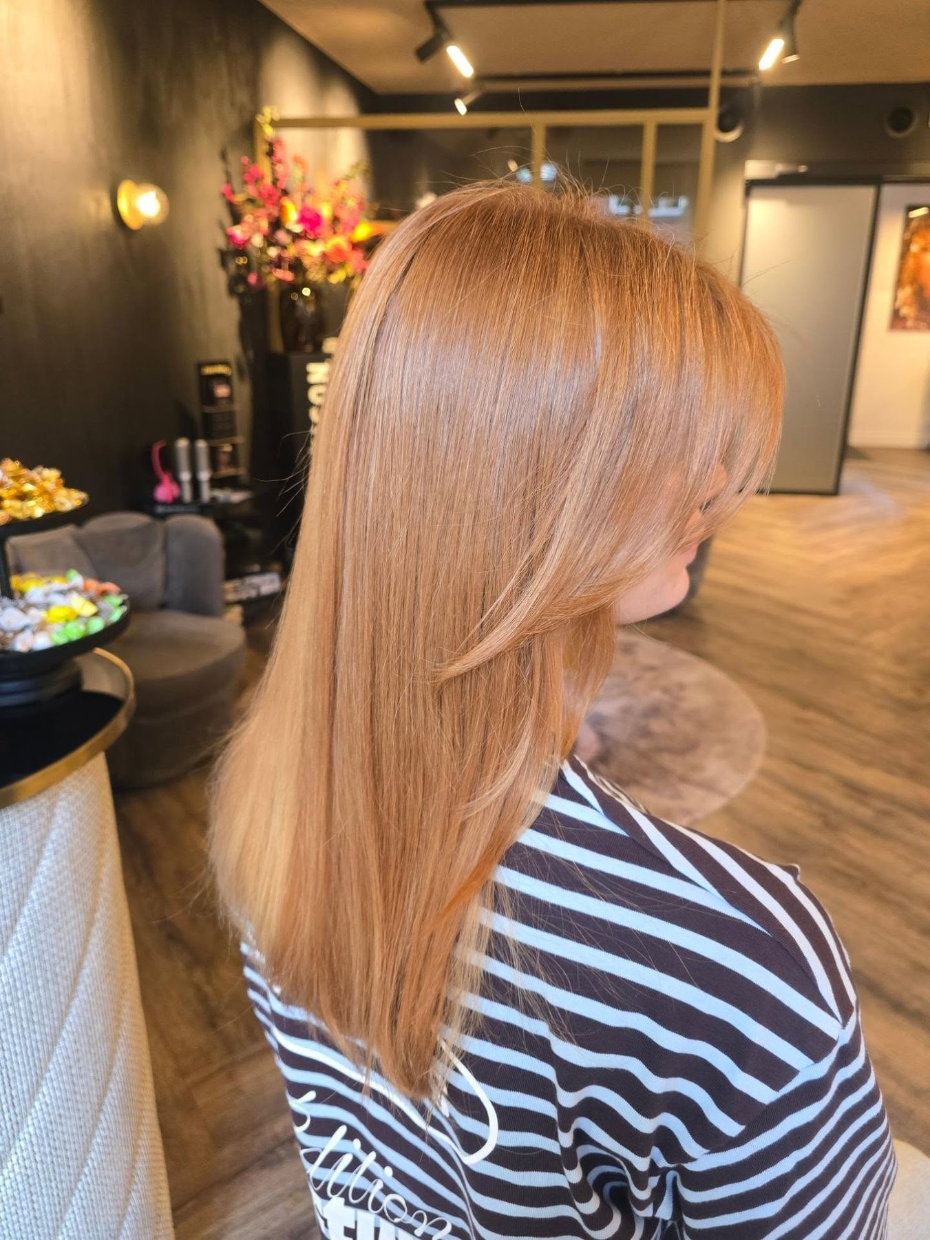 Lang, steil haar in een warme kopertint, in de salon